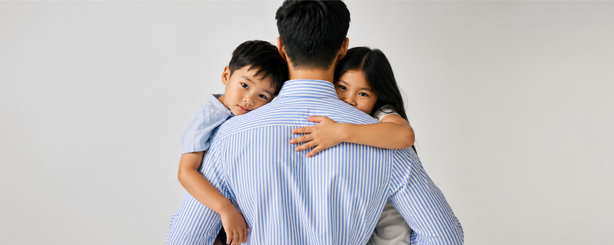 Man hugging two children on a plain background